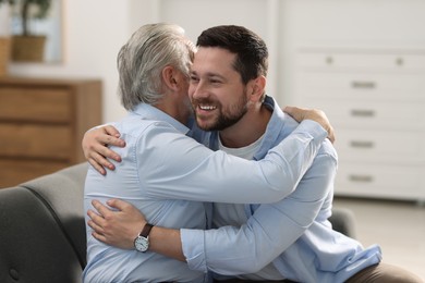 Photo of Happy son and his dad hugging at home