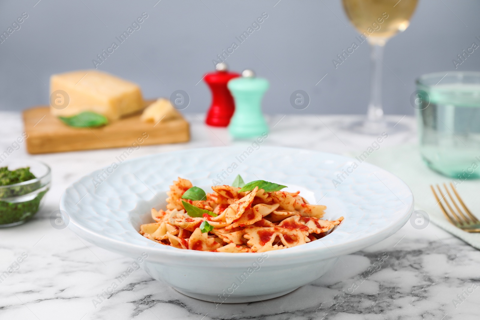 Photo of Tasty pasta with tomato sauce and basil on white marble table