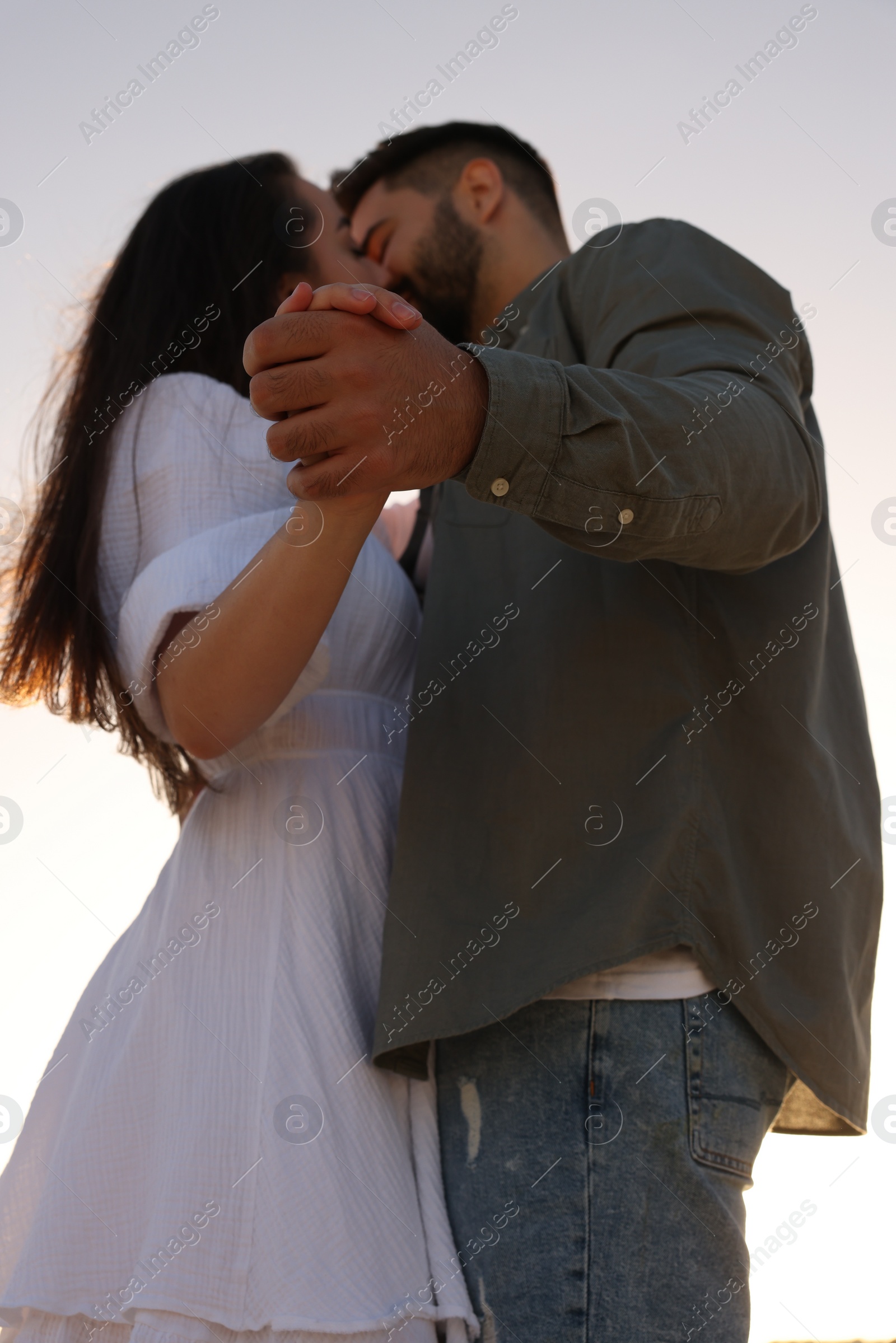 Photo of Beautiful couple dancing and kissing outdoors, low angle view