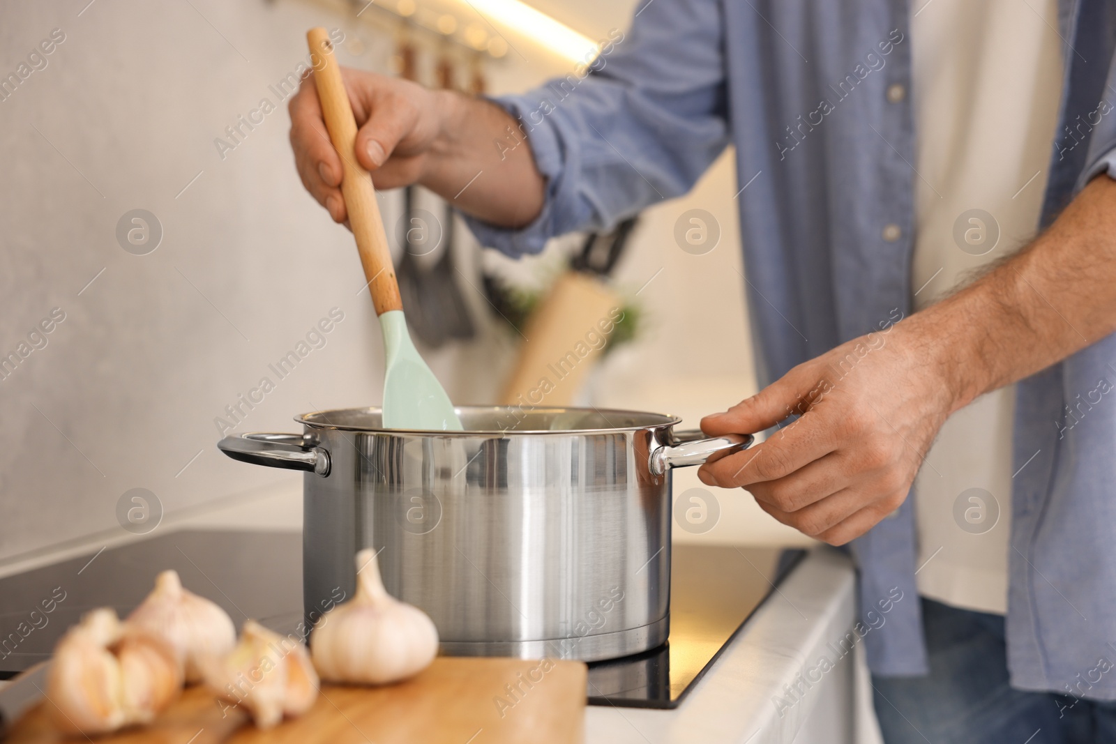 Photo of Man cooking delicious soup in kitchen, closeup