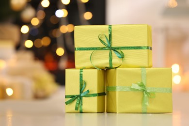 Photo of Beautifully wrapped gift boxes against blurred festive lights, space for text. Christmas celebration