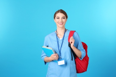 Photo of Young medical student with notebooks and backpack on color background. Space for text