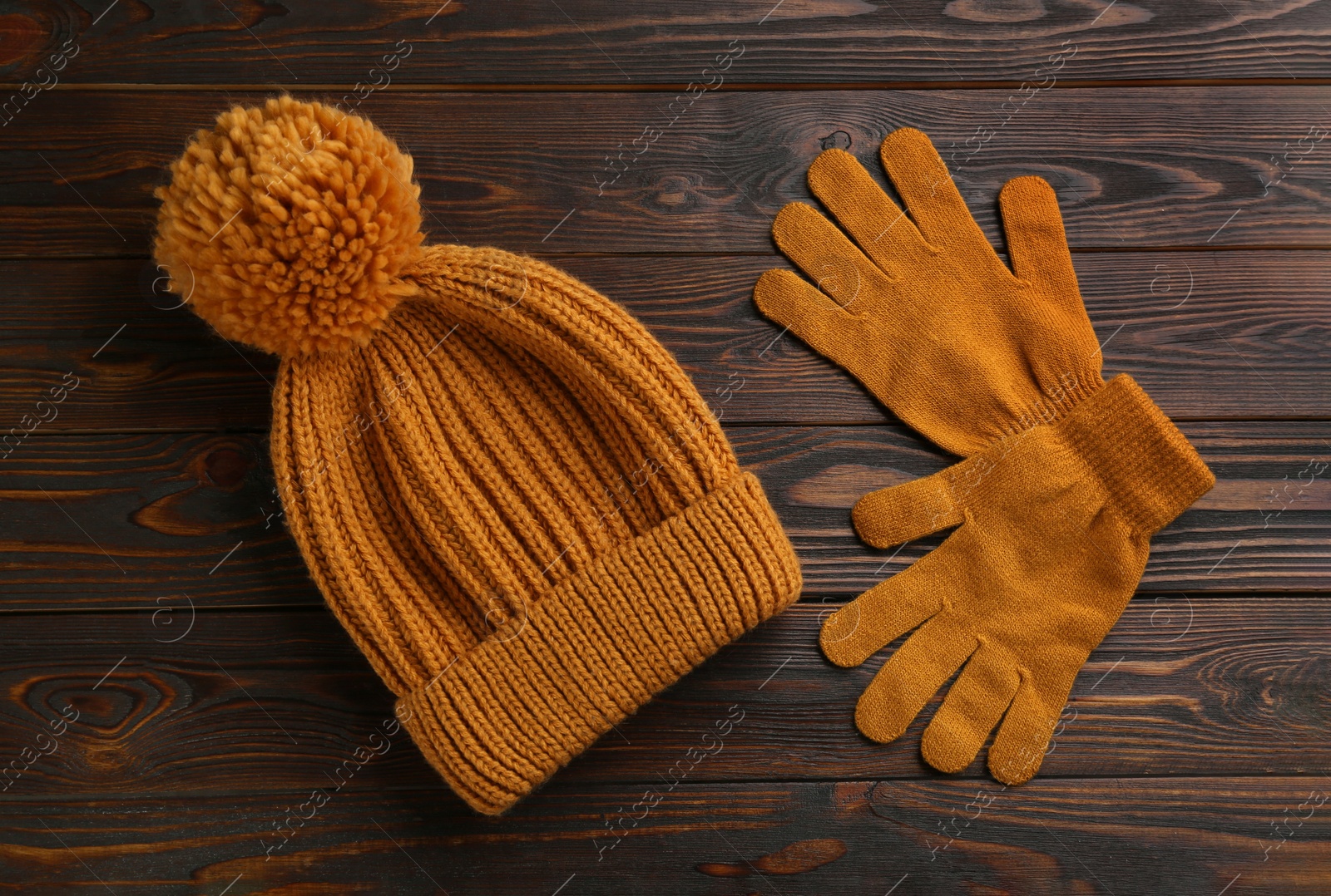 Photo of Woolen gloves and hat on wooden background, flat lay