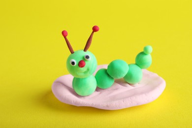 Photo of Colorful caterpillar made from play dough on yellow background, closeup