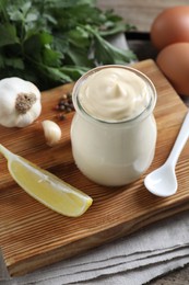 Fresh mayonnaise sauce in glass jar and ingredients on table, closeup