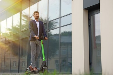 Photo of Businessman riding modern kick scooter on city street, space for text