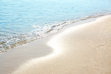 View of sea water and beach sand on sunny summer day