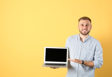 Photo of Portrait of handsome man with laptop on color background