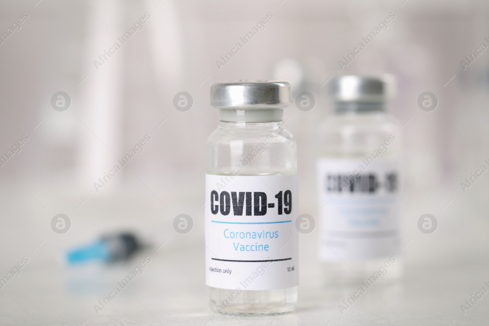 Photo of Vials and syringe with coronavirus vaccine on light table