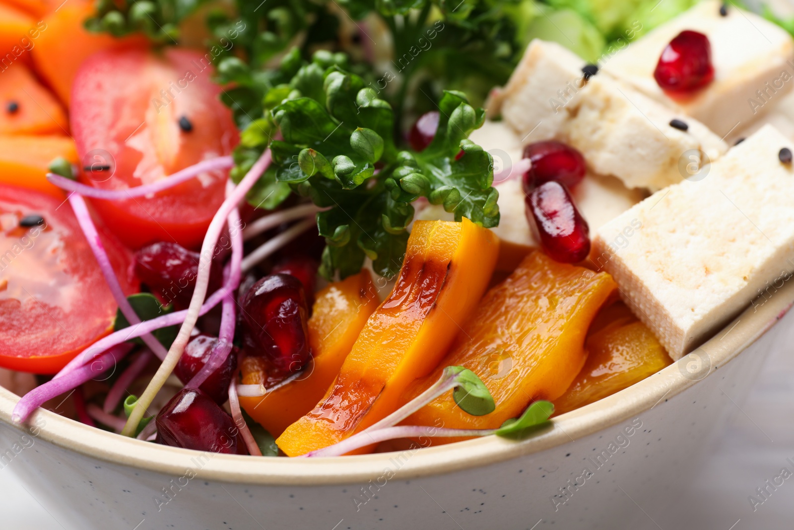 Photo of Bowl with many different vegetables on table, closeup. Vegan diet