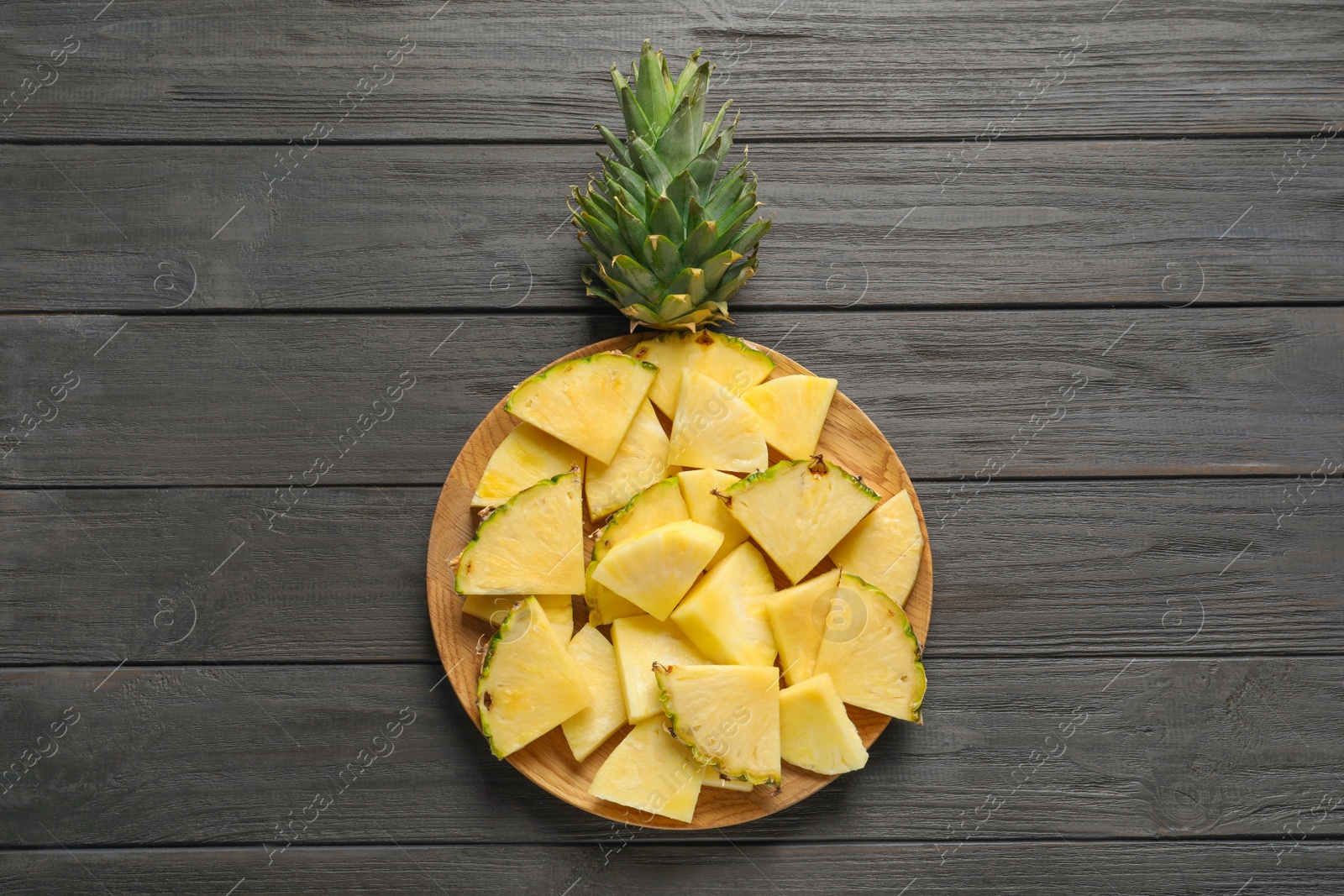 Photo of Plate with fresh sliced pineapple on wooden background