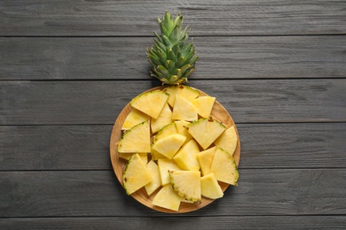 Plate with fresh sliced pineapple on wooden background