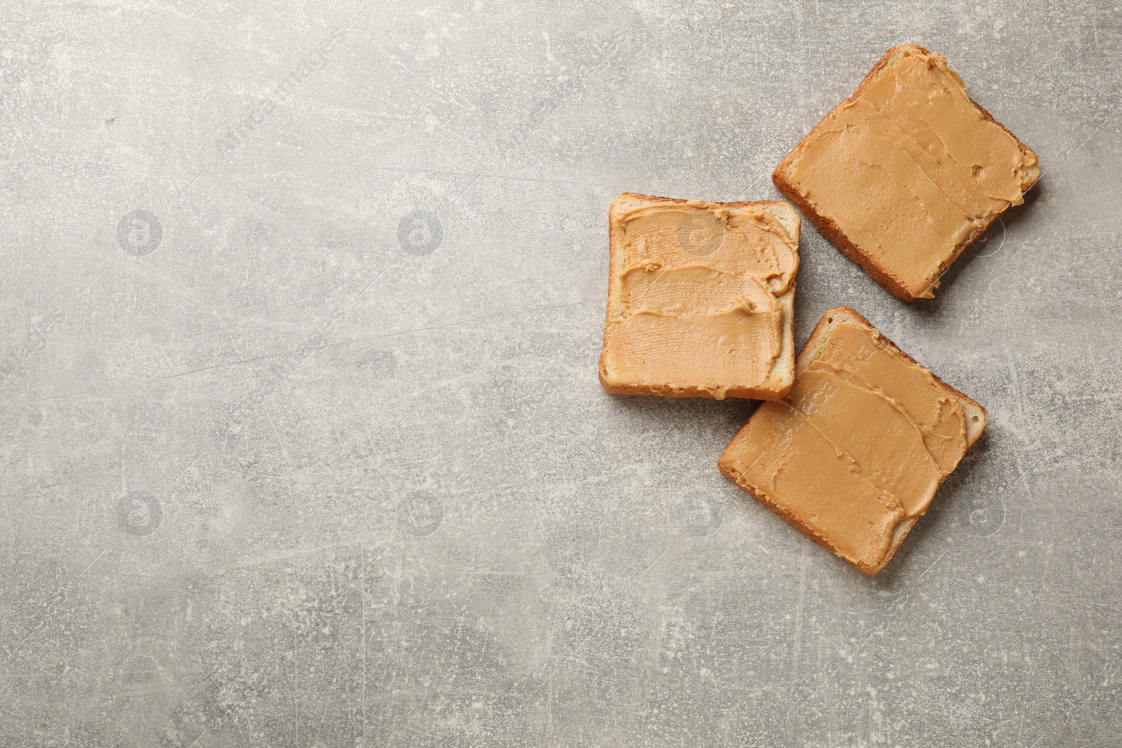 Photo of Tasty peanut butter sandwiches on gray table, flat lay. Space for text