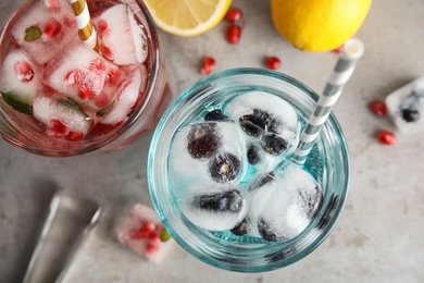 Tasty cocktails with fruit ice cubes and lemons on grey background, top view