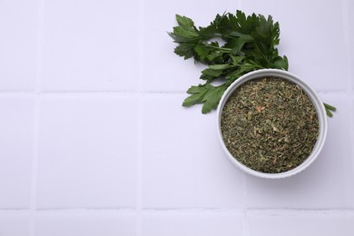 Photo of Dried parsley and fresh leaves on white tiled table, flat lay. Space for text