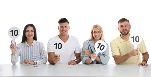 Photo of Panel of judges holding signs with highest score at table on white background