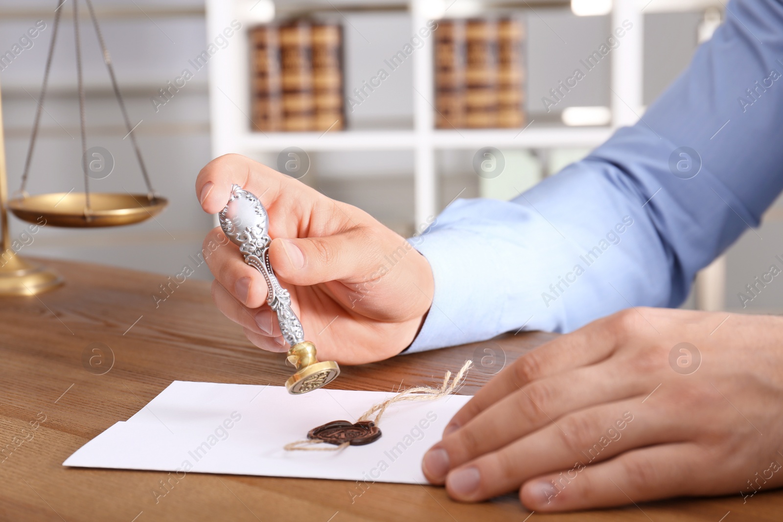 Photo of Male notary sealing document at table in office, closeup