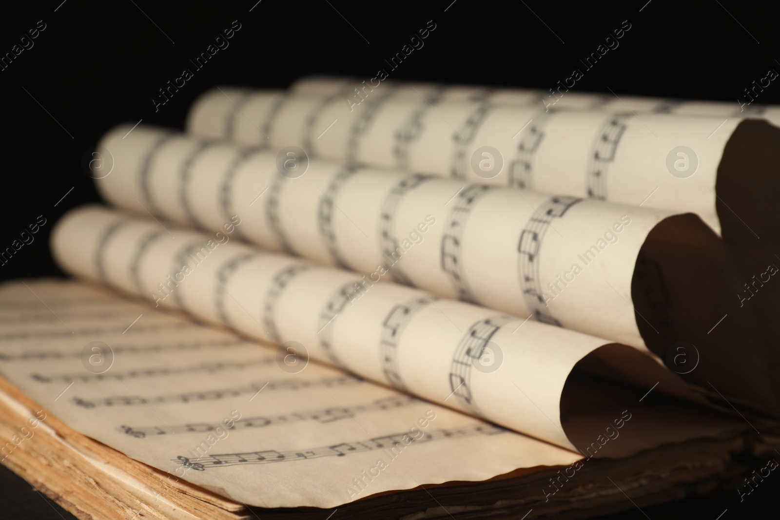 Photo of Old wrapped sheets with music notes on black background, closeup