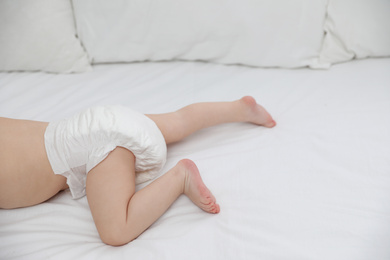 Cute little baby in diaper on bed, closeup