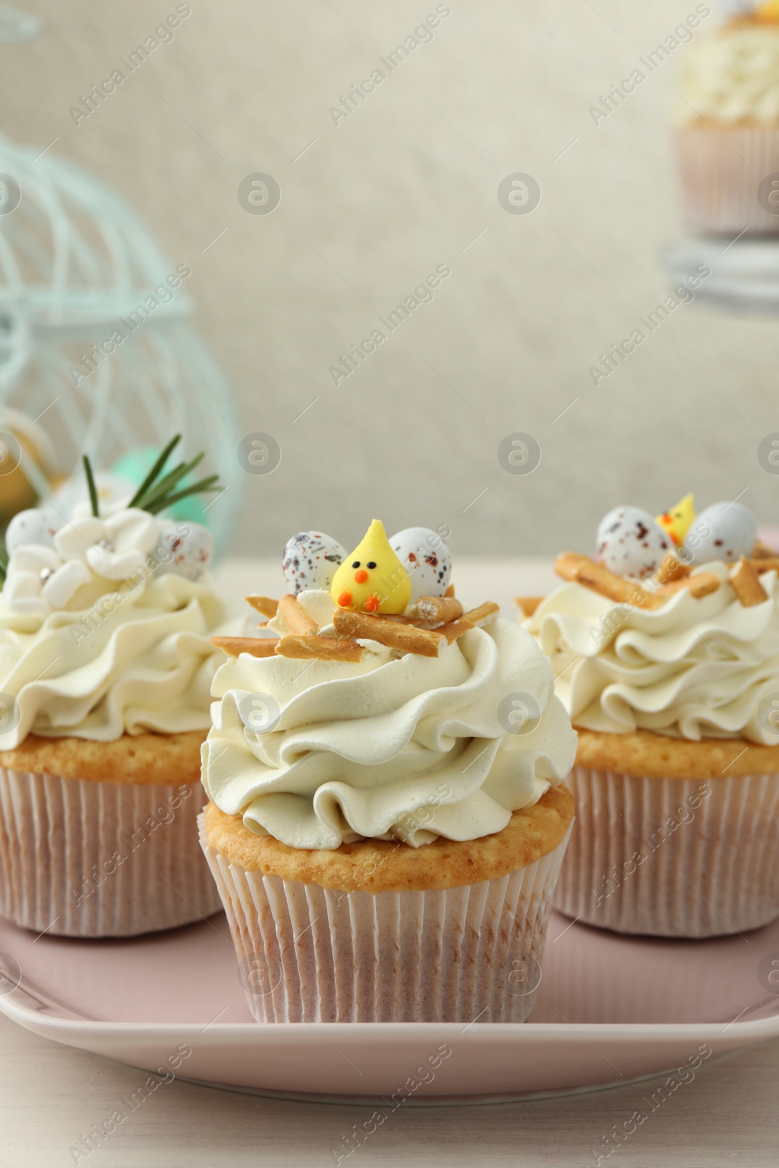 Photo of Tasty Easter cupcakes with vanilla cream on light wooden table