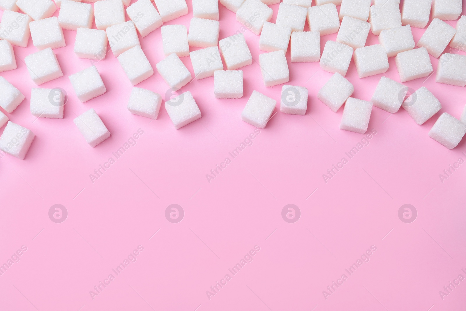 Photo of Refined sugar cubes on pink background, above view. Space for text