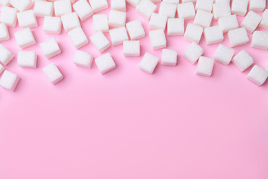 Refined sugar cubes on pink background, above view. Space for text