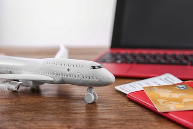 Composition with airplane model, passport and credit card on wooden table. Travel agency concept