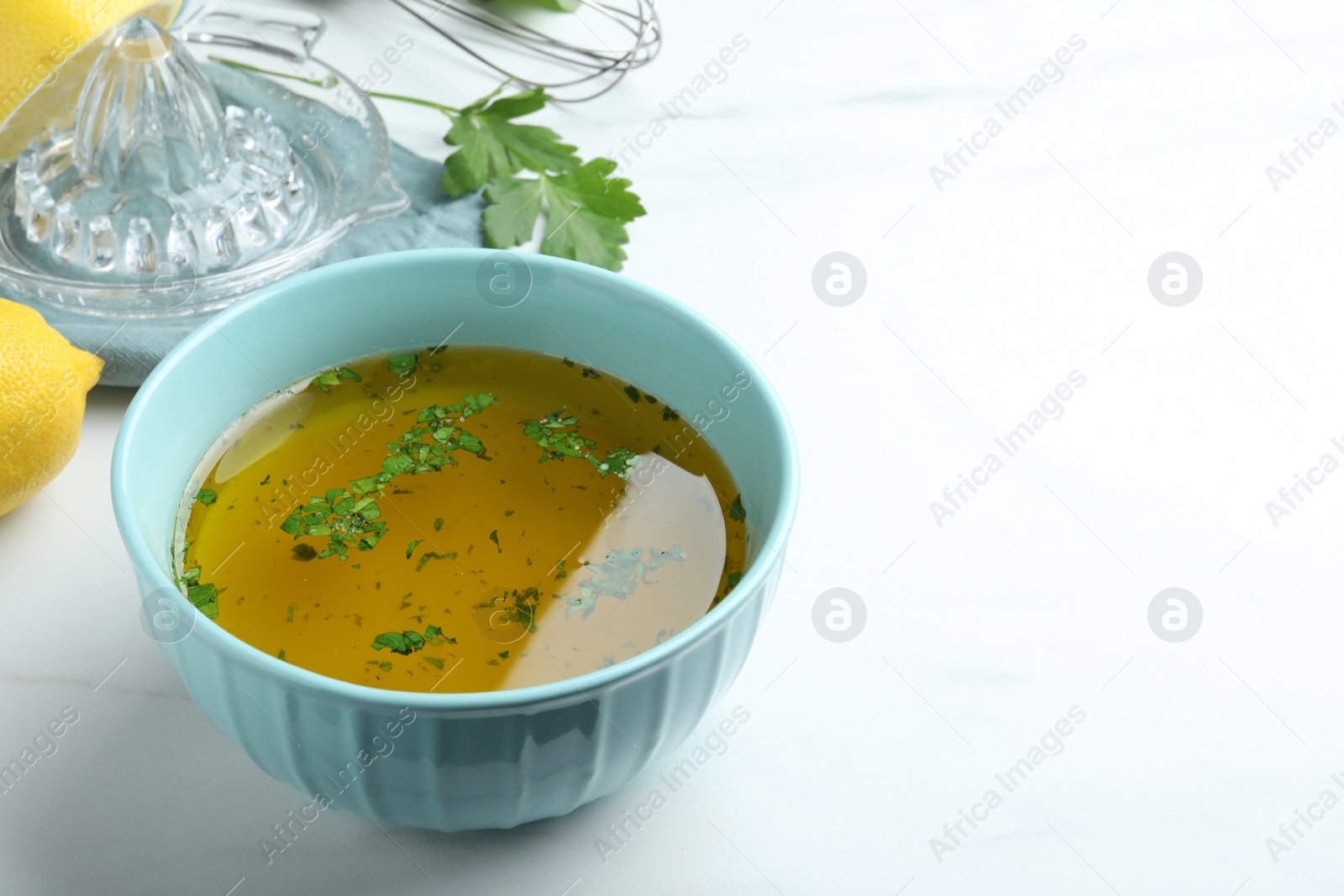 Photo of Bowl with lemon sauce on white table, space for text. Delicious salad dressing