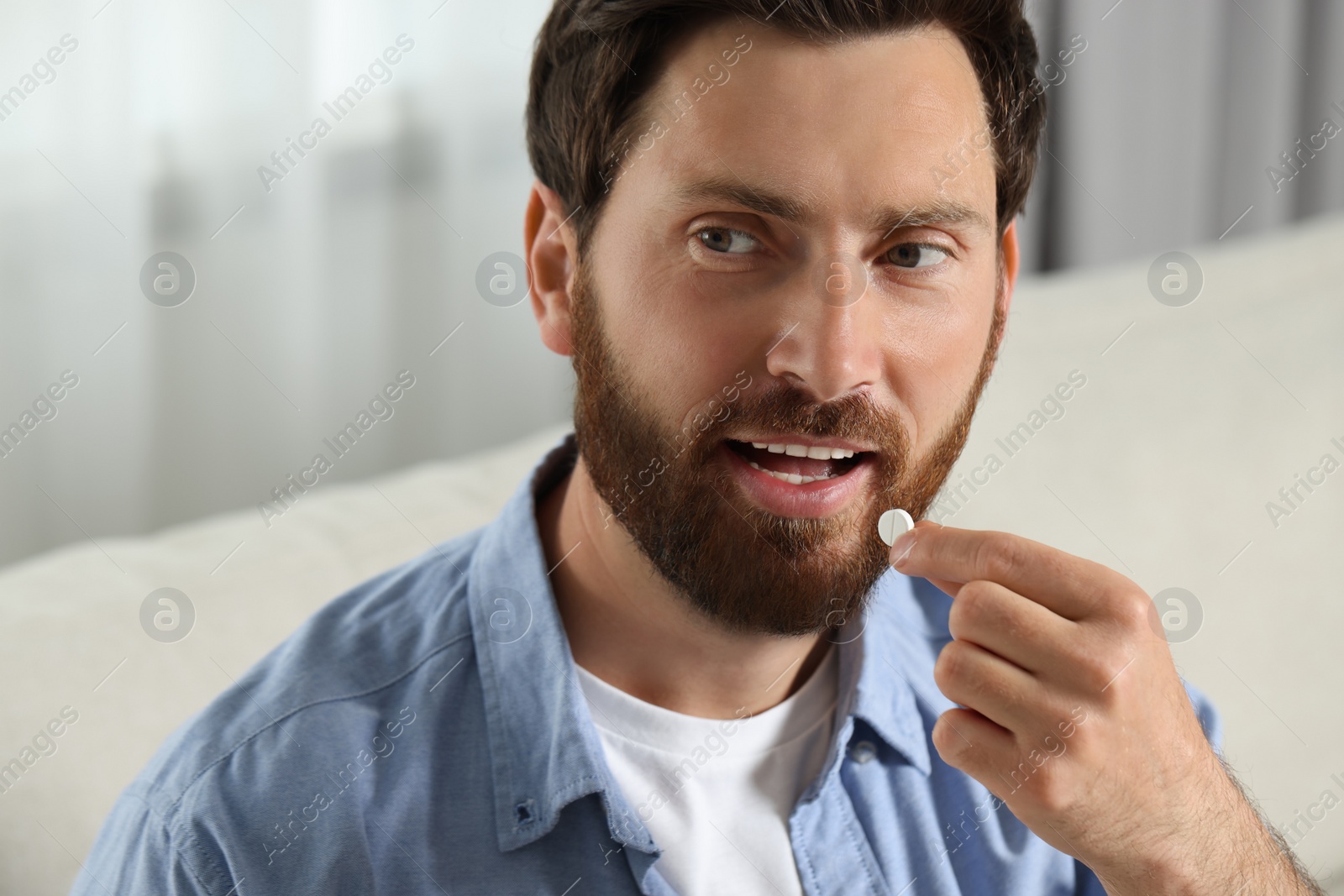 Photo of Portrait of handsome man taking pill indoors