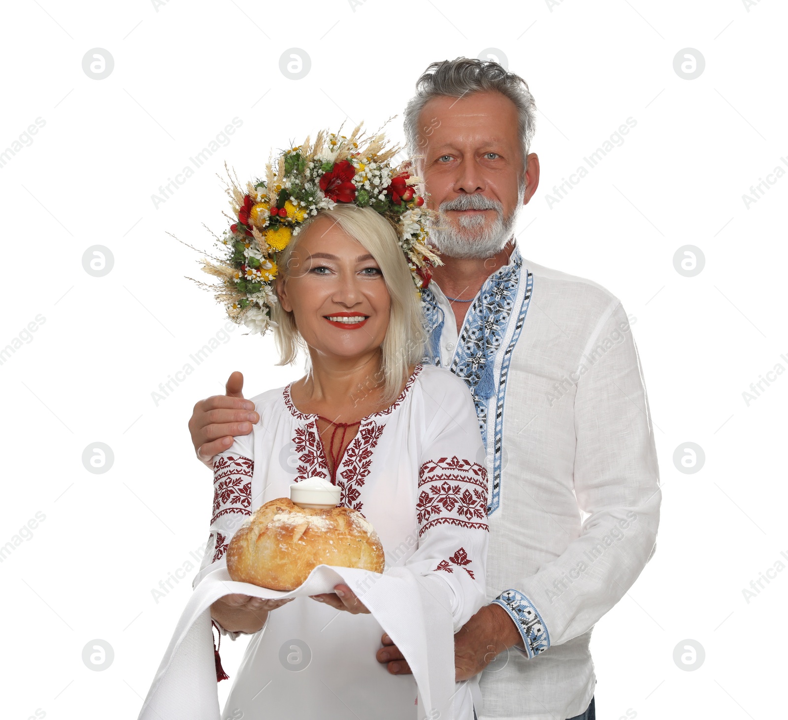 Photo of Happy mature couple in national clothes with bread and salt on white background. Ukrainian welcoming tradition