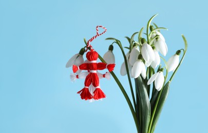 Photo of Traditional martisor and beautiful snowdrops on light blue background. Symbol of first spring day