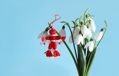 Traditional martisor and beautiful snowdrops on light blue background. Symbol of first spring day