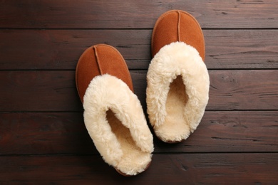 Photo of Pair of stylish soft slippers on wooden background, flat lay