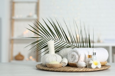 Composition with different spa products and plumeria flower on white table indoors