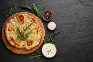 Photo of Delicious khachapuri with cheese served on black table, flat lay. Space for text