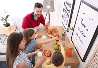 Photo of Happy family having breakfast with milk at table