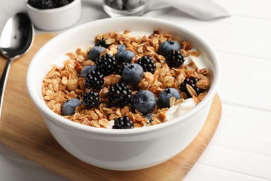 Photo of Bowl of healthy muesli served with berries on white wooden table, closeup