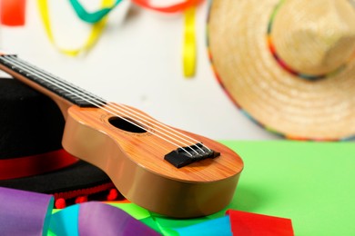 Photo of Black Flamenco hat and ukulele on green table, closeup. Space for text