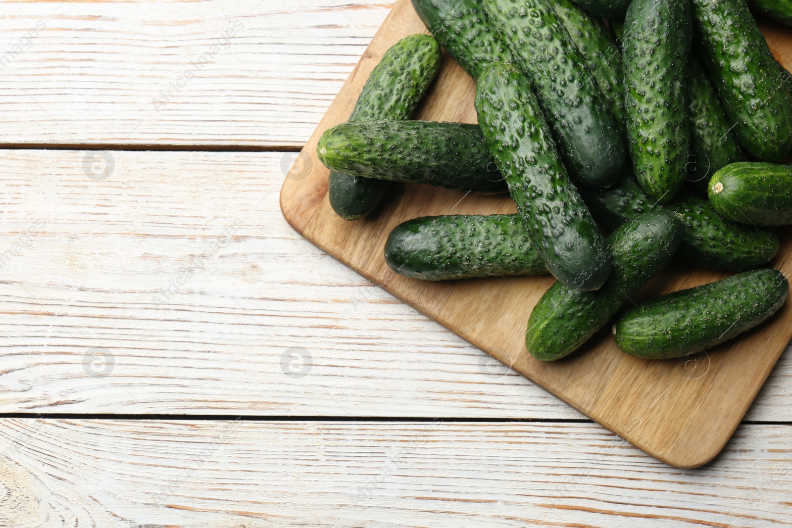 Photo of Fresh ripe cucumbers on white wooden table, top view. Space for text