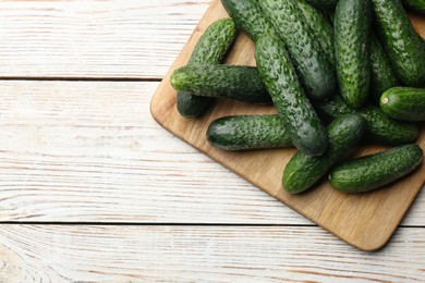 Fresh ripe cucumbers on white wooden table, top view. Space for text