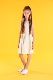 Photo of Full length portrait of cute little girl on yellow background