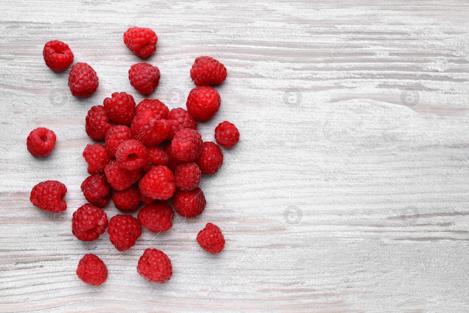 Photo of Tasty ripe raspberries on white wooden table, flat lay. Space for text