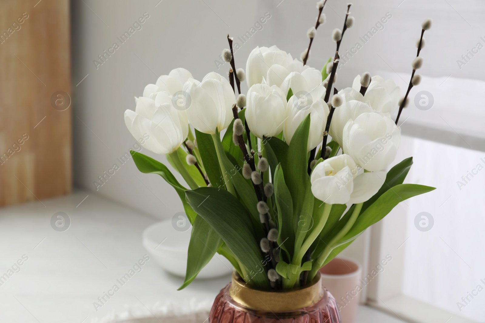 Photo of Beautiful bouquet of willow branches and tulips in vase indoors, space for text