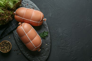 Flat lay composition with tasty boiled sausages on dark textured table. Space for text