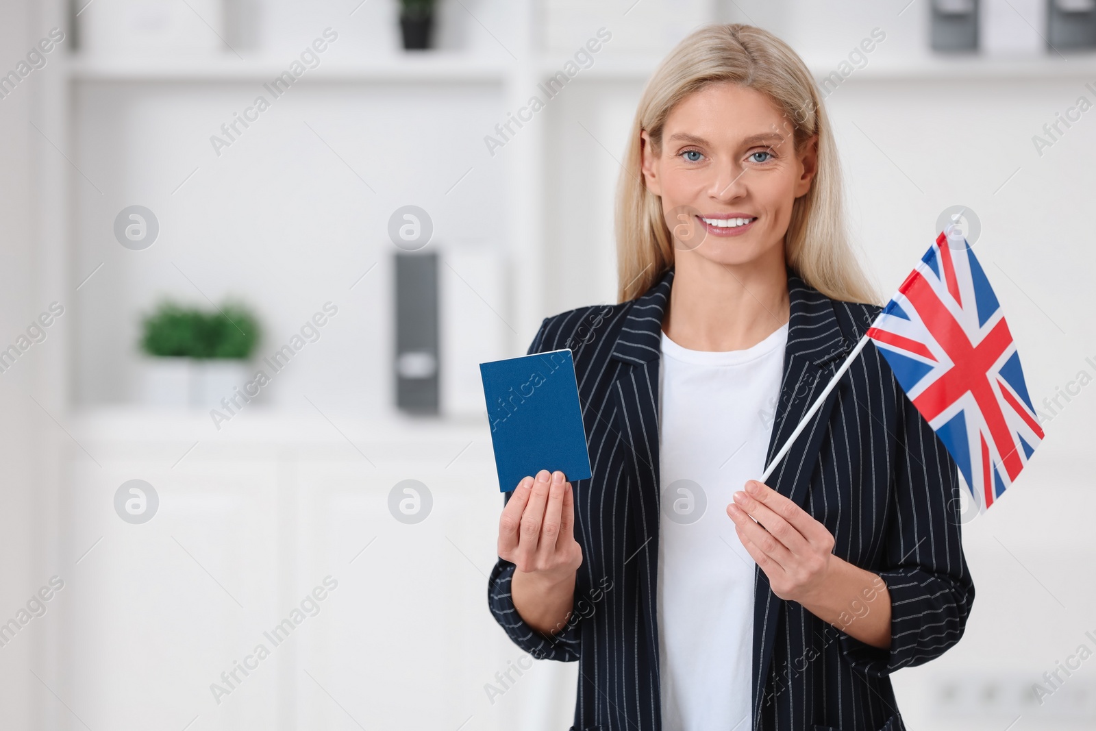 Photo of Immigration. Happy woman with passport and flag of United Kingdom indoors, space for text