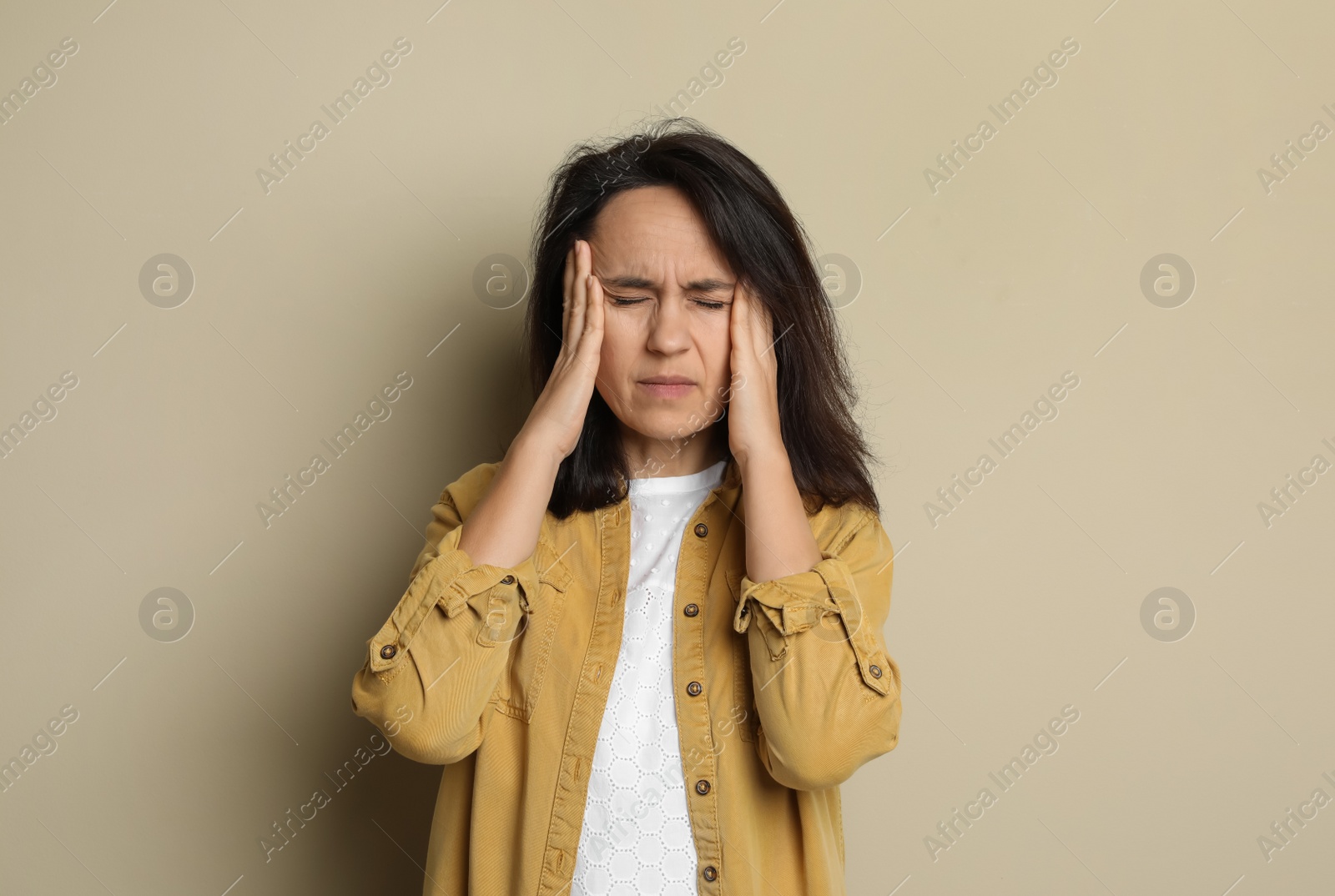 Photo of Mature woman suffering from headache on beige background