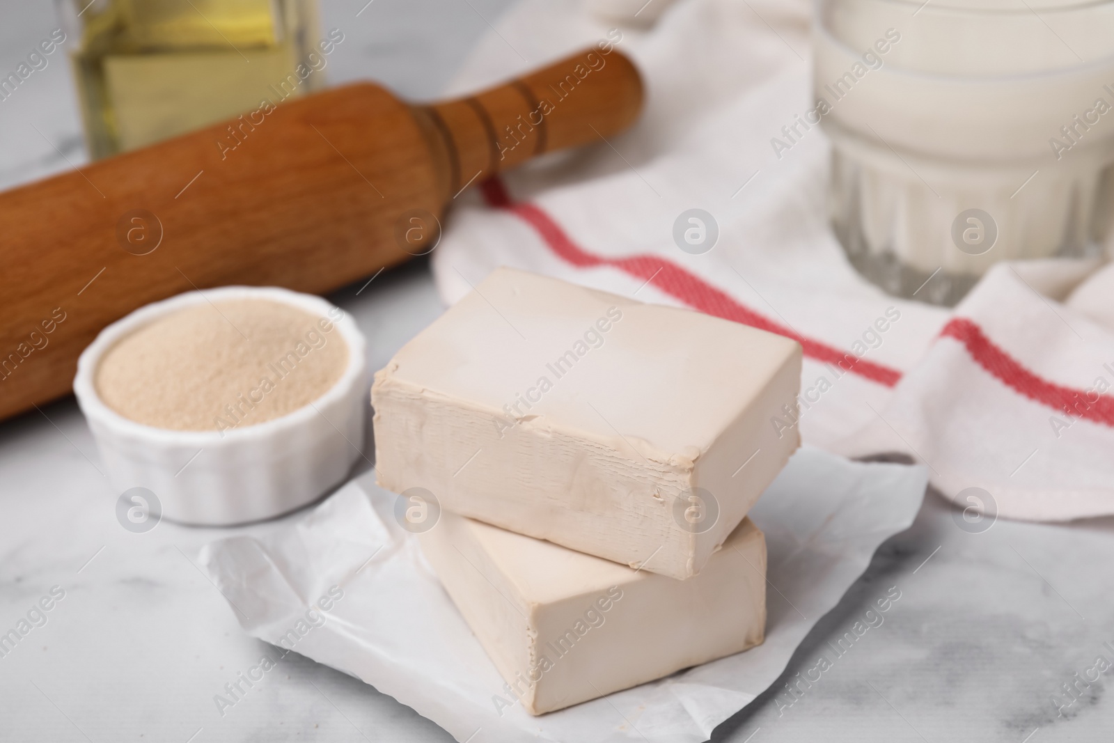 Photo of Granulated and compressed yeast on white marble table, closeup