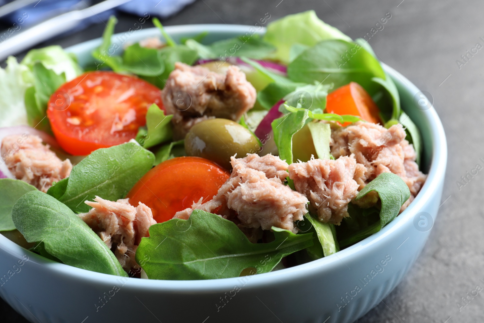 Photo of Bowl of delicious salad with canned tuna and vegetables on black table, closeup