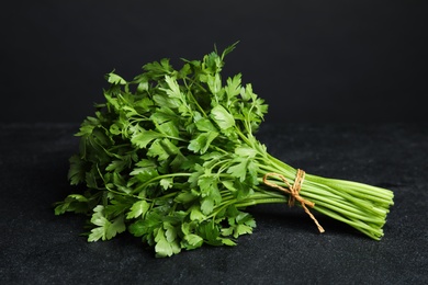 Photo of Bunch of fresh green parsley on dark table