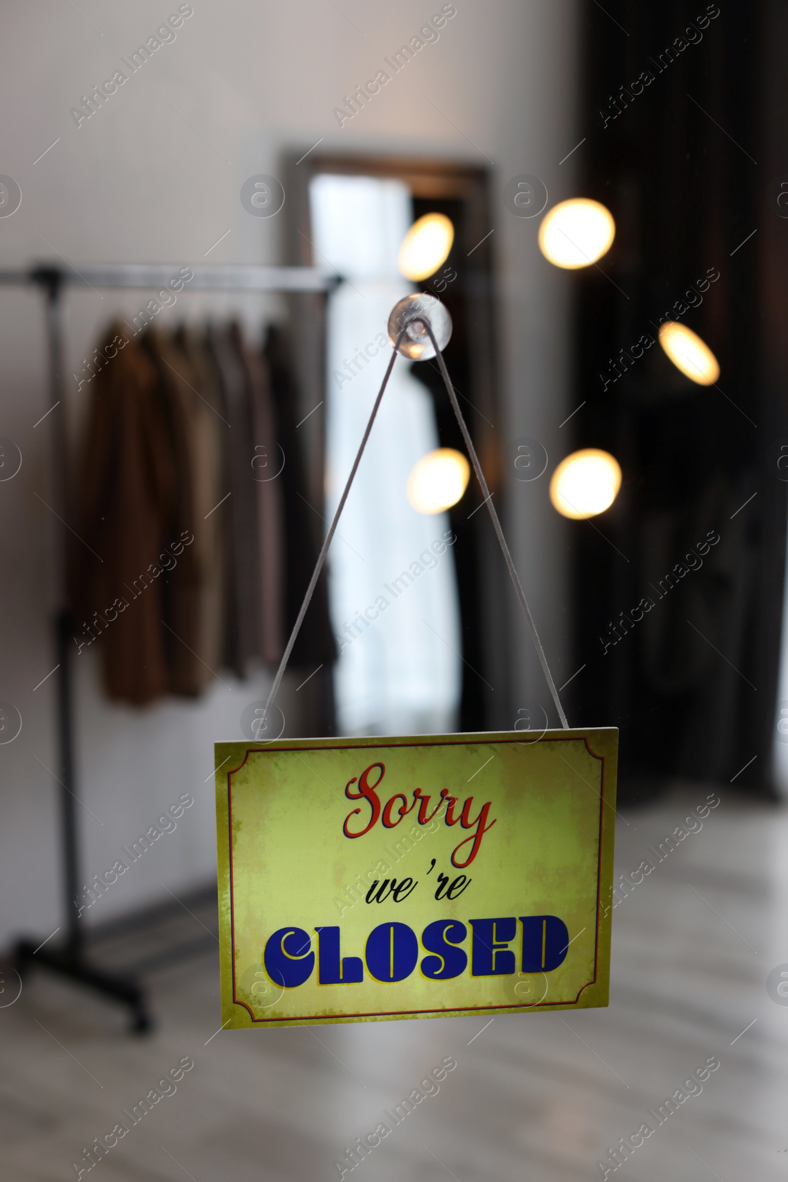 Photo of Yellow sign with text Sorry we're Closed hanging on glass door. Coronavirus quarantine